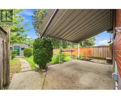 A backyard with a concrete pathway and a wooden fence.