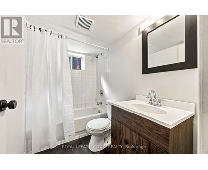 A white bathroom with a toilet, sink, and shower.