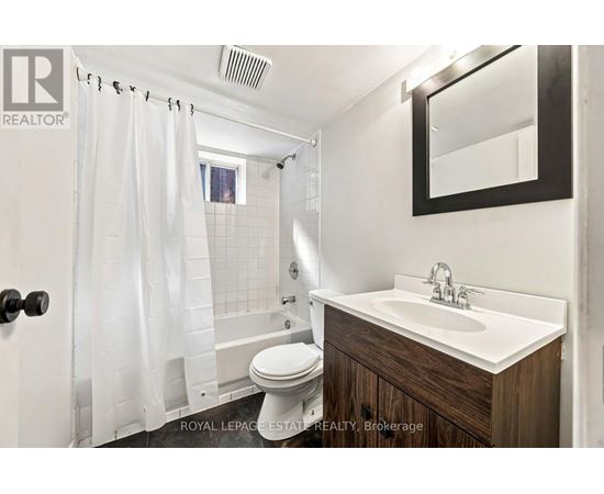 A white bathroom with a toilet, sink, and shower.
