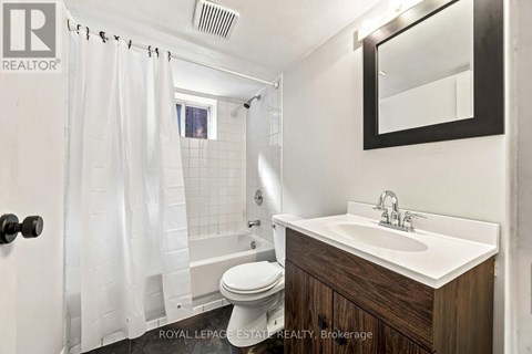 A white bathroom with a toilet, sink, and shower.