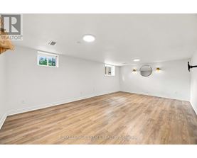 A spacious room with wooden flooring and white walls.