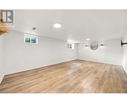 A spacious room with wooden flooring and white walls.