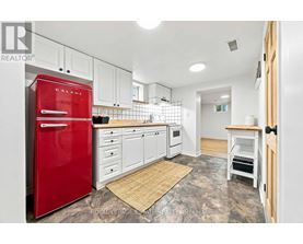 A kitchen with a red fridge and white cabinets.