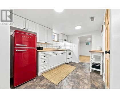 A kitchen with a red fridge and white cabinets.