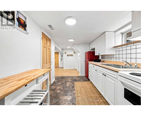 A kitchen with white cabinets and a red fridge.