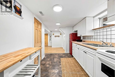 A kitchen with white cabinets and a red fridge.