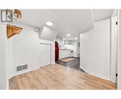 A spacious room with wooden flooring and white walls.