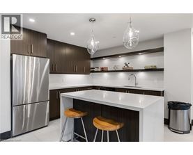 A modern kitchen with a stainless steel refrigerator, bar stools, and a white countertop.