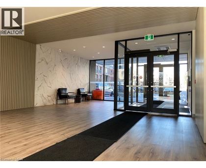 A modern office lobby with a black and white rug, a wooden floor, and a glass door leading outside.
