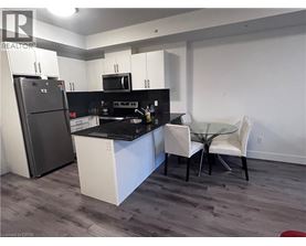 A kitchen with a refrigerator, microwave, and a dining table with chairs.