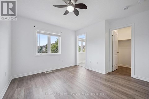 A room with a ceiling fan and a window with a view of trees.