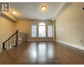 A spacious room with wooden flooring and a staircase leading to the upper level.
