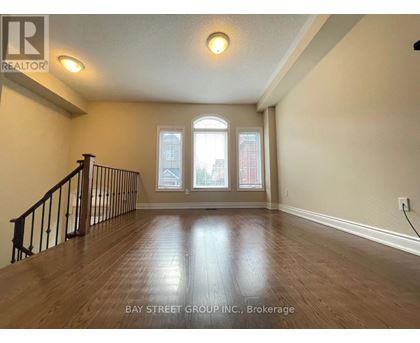 A spacious room with wooden flooring and a staircase leading to the upper level.