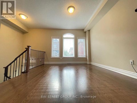 A spacious room with wooden flooring and a staircase leading to the upper level.
