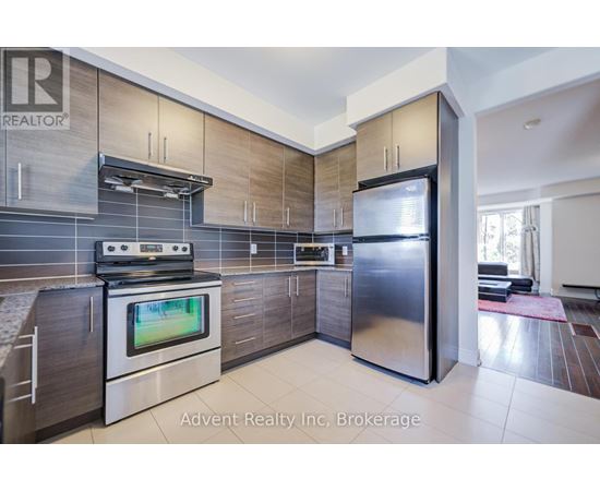 A modern kitchen with a stainless steel refrigerator and a flat screen TV built into the cabinetry.