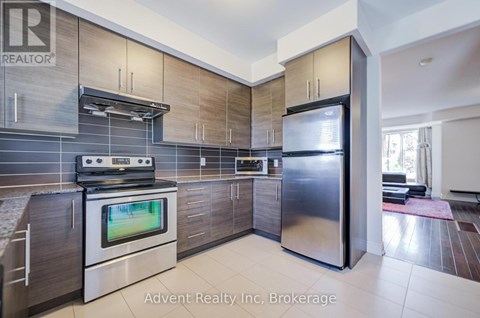 A modern kitchen with a stainless steel refrigerator and a flat screen TV built into the cabinetry.
