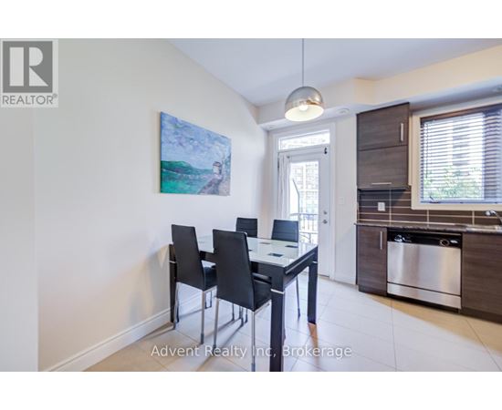 A dining room with a table and chairs and a painting on the wall.