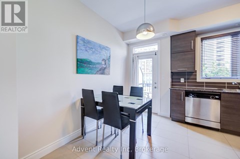 A dining room with a table and chairs and a painting on the wall.