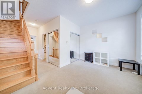 A spacious room with a staircase, a black dresser, a white shelf, and a black table.