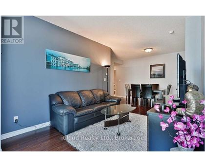 A living room with a black leather couch and a painting on the wall.