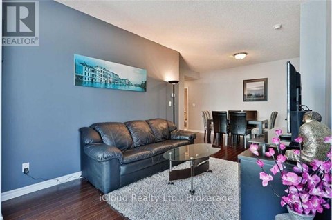 A living room with a black leather couch and a painting on the wall.
