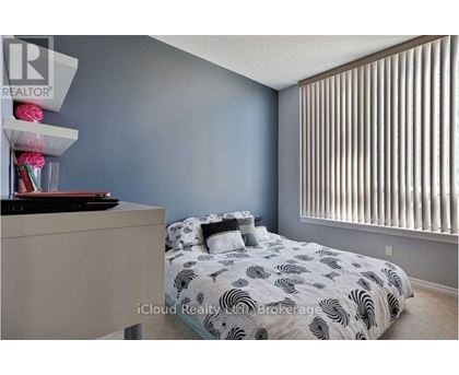 A bedroom with a bed, nightstand, and a window with blinds.