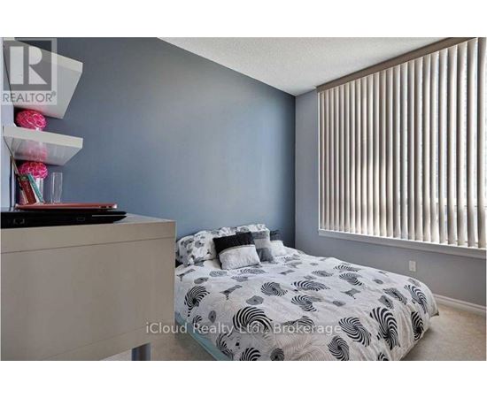 A bedroom with a bed, nightstand, and a window with blinds.