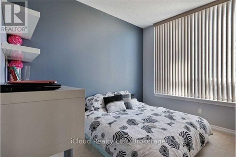 A bedroom with a bed, nightstand, and a window with blinds.