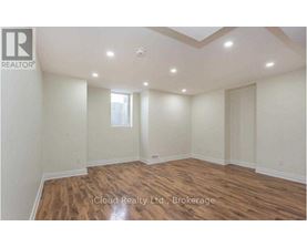 A spacious room with wooden flooring and a skylight.