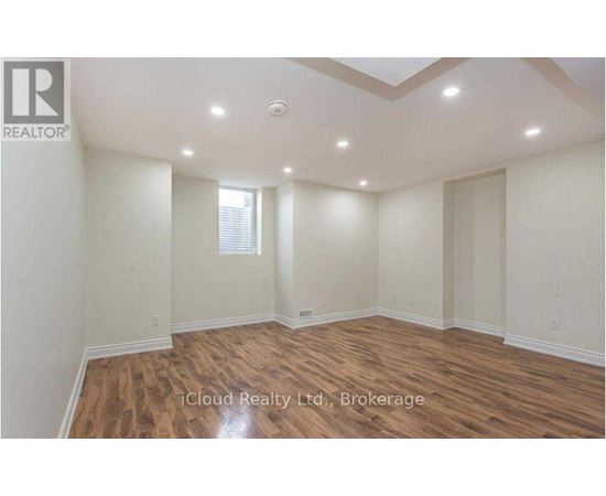 A spacious room with wooden flooring and a skylight.