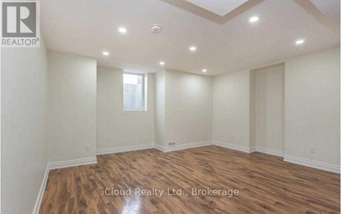 A spacious room with wooden flooring and a skylight.