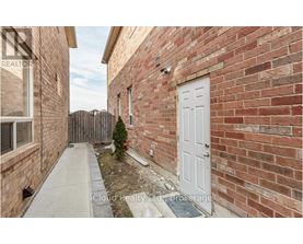 A small white door is on the side of a brick building.