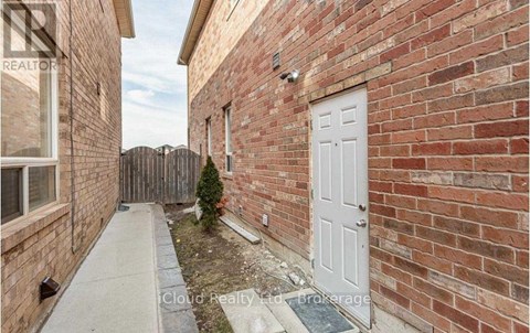 A small white door is on the side of a brick building.