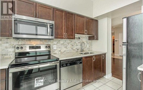 A kitchen with brown cabinets and stainless steel appliances.