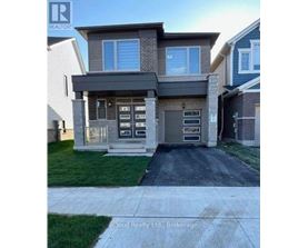 A modern house with a grey front yard and a driveway.