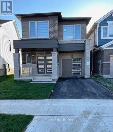 A modern house with a grey front yard and a driveway.