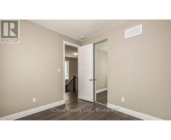 A room with a white door and a brokerage sign on the wall.