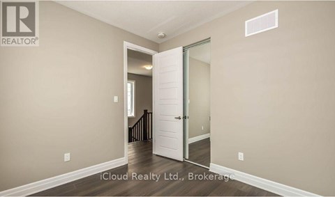 A room with a white door and a brokerage sign on the wall.