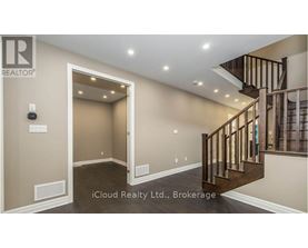 A spacious hallway with a staircase and a door leading to another room.