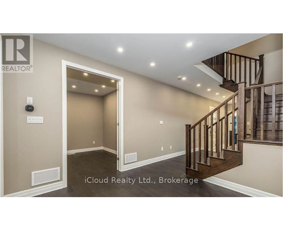 A spacious hallway with a staircase and a door leading to another room.