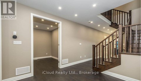 A spacious hallway with a staircase and a door leading to another room.