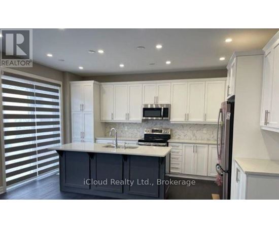 A kitchen with white cabinets and a central island with a sink.