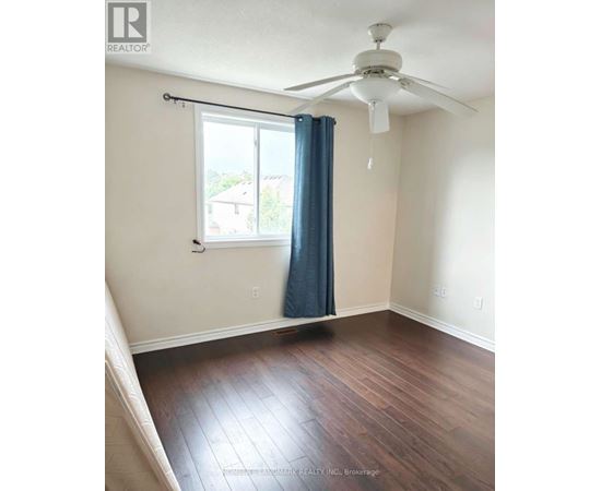 A room with a ceiling fan and a window with a blue curtain.