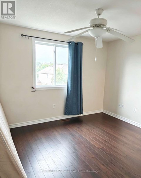 A room with a ceiling fan and a window with a blue curtain.