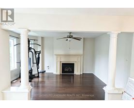 A spacious living room with a fireplace and exercise equipment.