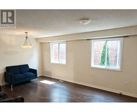 A living room with a blue couch and a window with a tree outside.
