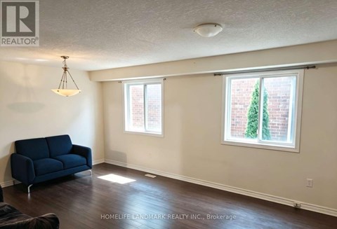 A living room with a blue couch and a window with a tree outside.