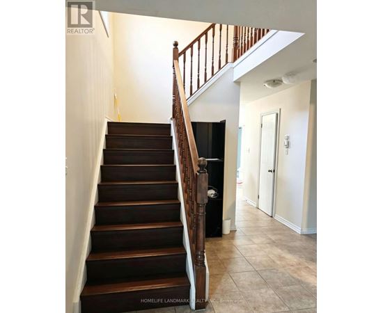 A staircase with a wooden handrail and dark brown steps.