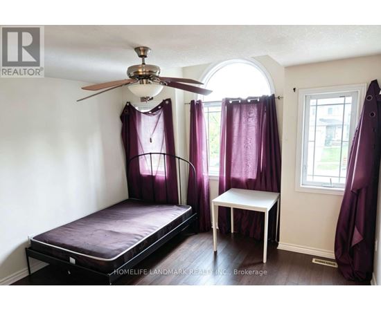 A bedroom with a bed, a small table, and a window with purple curtains.
