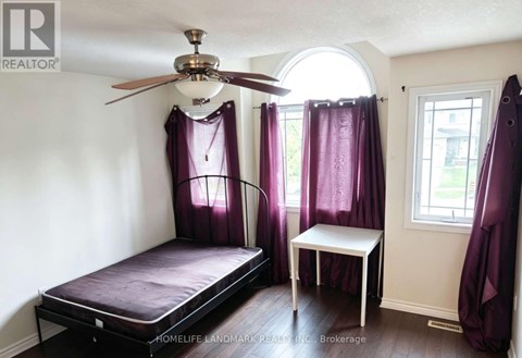 A bedroom with a bed, a small table, and a window with purple curtains.